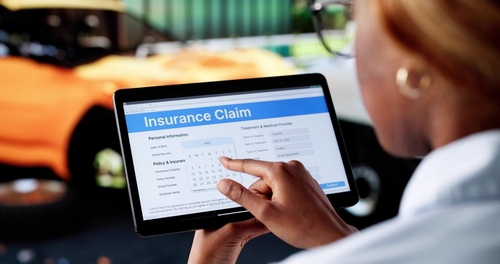 person completing Insurance Claim form on tablet near vehicle